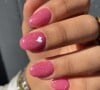 Unha com esmalte de glitter cor de rosa e coração em branco no dedo médio traz inspiração Barbiecore