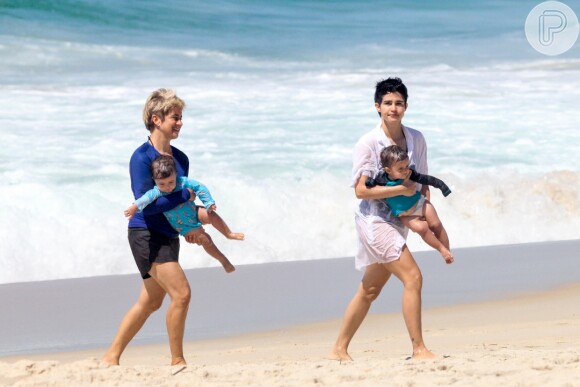 Nanda Costa e Lan Lanh carregaram as filhas gêmeas no colo em dia de praia