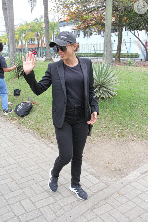 Anitta vestiu um conjunto de calça e blazer pretos, combinados com tênis