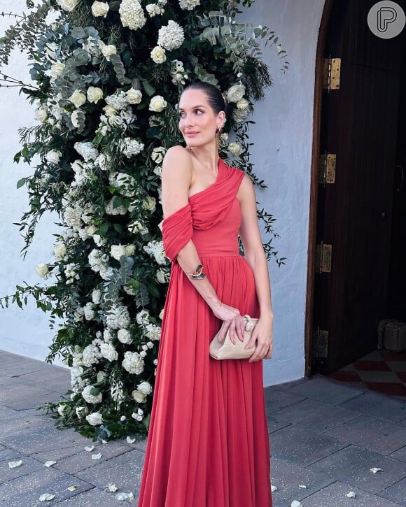 Vestido de festa vermelho de Schynaider foi combinado com um bracelete e bolsa pequena bege