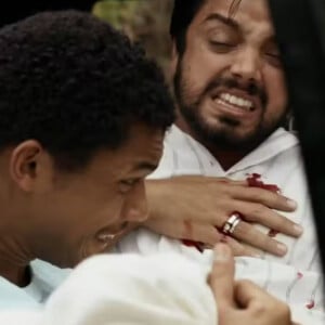 Em 'Renascer', João Pedro (Juan Paiva) leva Venâncio (Rodrigo Simas) no colo após ser atingido por uma bala.