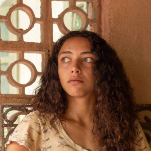 Joana (Alice Carvalho) nega para Tião (Irandhir Santos) que Egídio esteja lhe assediando, mas deixa o marido desconfiado.