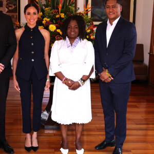 O conjunto que Meghan Markle usou tinha uma blusa de botão sem alças, com gola, e calça em alfaiataria. 
