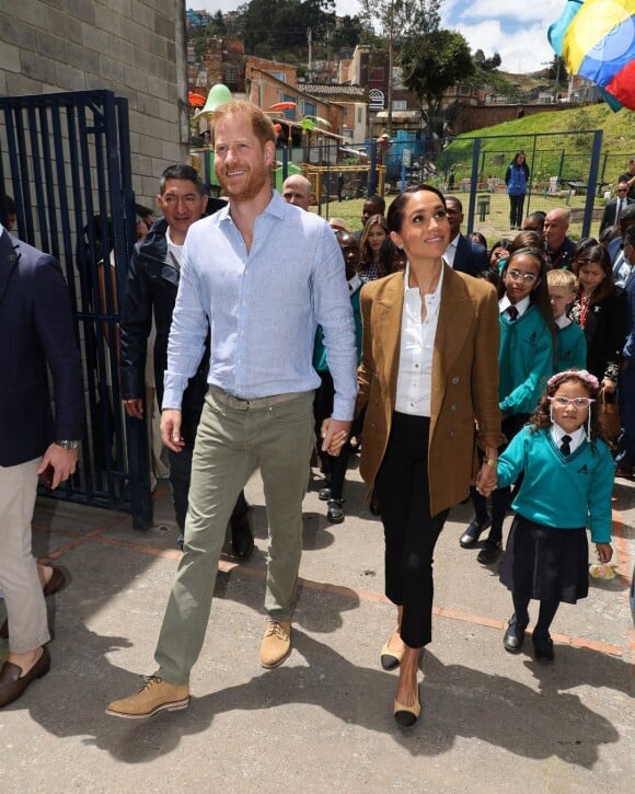 Outra proposta chique e atemporal, o blazer mais alongado, foi uma das apostas de Meghan Markle. Neste caso, ela compôs com uma blusa clara, ao fundo.