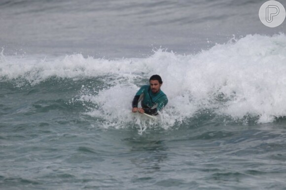 Cauã Reymond deita na prancha durante surfe