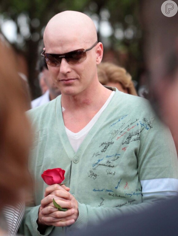 Reynaldo Gianecchini segura uma rosa no enterro do pai em Ribeirão Preto, em outubro de 2011, com a cabeça raspada por causa da quimioterapia