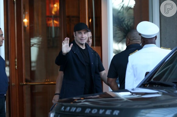 John Travolta acena para os fotógrafos de plantão na porta do hotel, no Rio