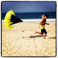 Carolina Dieckmann faz exercícios na areia da praia usando um paraquedas