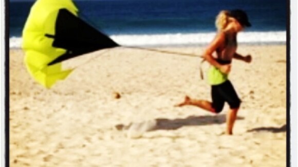 Carolina Dieckmann faz exercícios na areia da praia usando um paraquedas