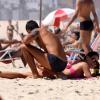 Carolina Ferraz gargalha enquanto namorado passa protetor solar nela