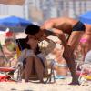Carolina Ferraz troca carícias com o namorado na praia do Leblon, no Rio
