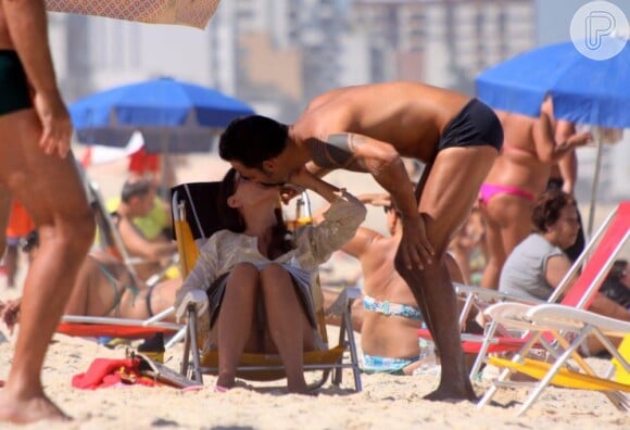 Carolina Ferraz troca carícias com o namorado na praia do Leblon, no Rio