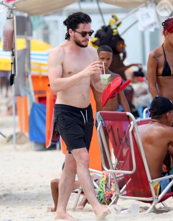 Descalço e somente de bermuda, Kit Harington bebe uma caipirinha no Rio