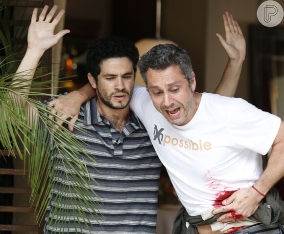 Romero Rômulo (Alexandre Nero) já levou um tiro ao mediar a negociação com bandidos durante um assalto e se tornou verdadeiramente um herói, em cena da novela 'A Regra do Jogo'