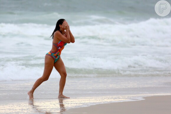 Carol Castro usou um maiô colorido e decotado para aproveitar a praia da Joatinga
