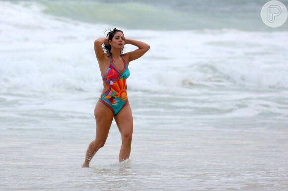 Carol Castro arruma o cabelo ao sair do mar, na praia da Joatinga