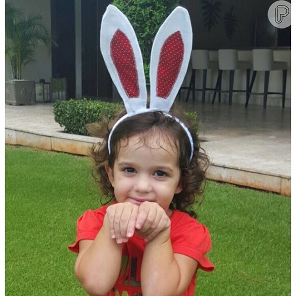 A filha caçula do casal imita um coelhinho na Páscoa