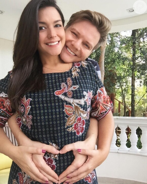 Abraçada ao marido, Michel Teló, Thais Fersoza usa vestido estampado que marca sua barriga de grávida