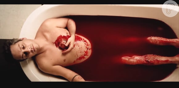 Alexandre Nero aparece em uma banheira de sangue, segurando o coração do porco no clipe de 'Carinhoso'