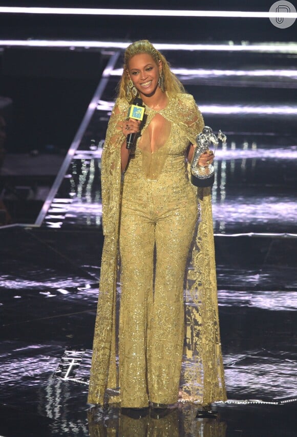 Beyoncé desfilou um macacão longo dourado e brilhoso nos palcos da premiação, onde subiu para receber um dos seus cinco prêmios conquistados da noite. O macacão estava acompanhado de uma capa em renda bordada