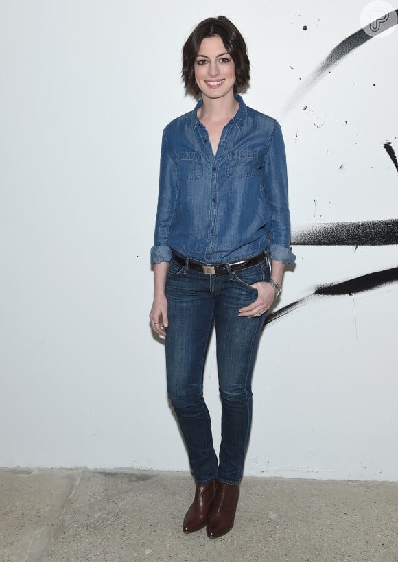A atriz Anne Hathaway usou cintos e botas mais escuras para destacar a tendência total jeans 