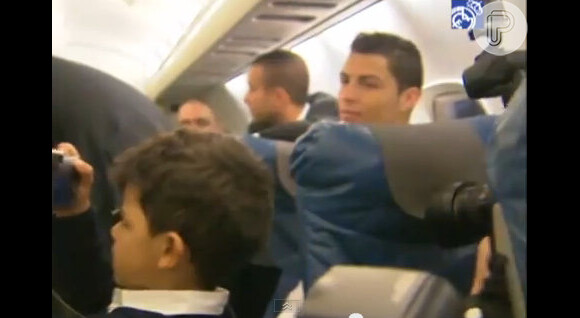 O atacante Cristiano Ronaldo vigia o filho, que tira fotos da festa no jatinho do Real Madrid
