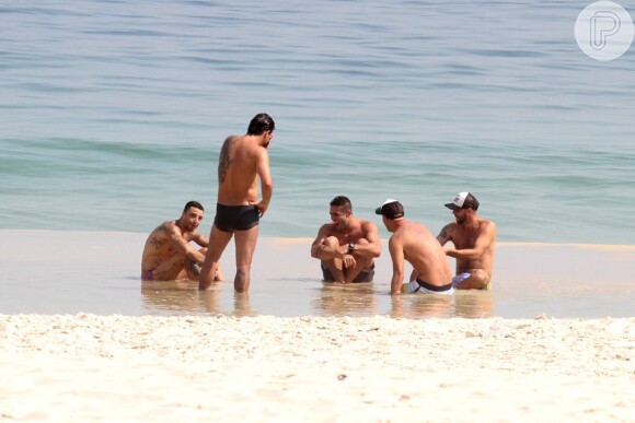 Felipe Titto ficou sentado na beira do mar conversando com amigos, entre eles o ex-BBB Yuri Fernandes