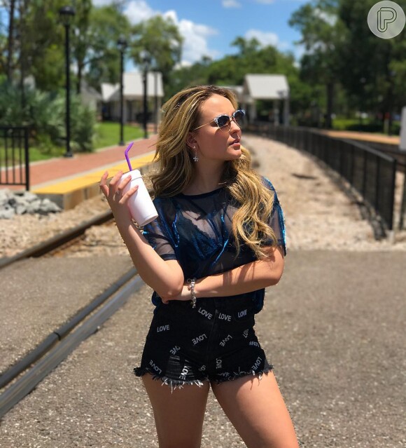 Larissa Manoela adotou a tendência da blusa holográfica em viagem aos parques da Disney