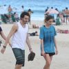 Carol Duarte e Gabriel Stauffer caminham juntos pela praia em gravação de 'A Força do Querer'