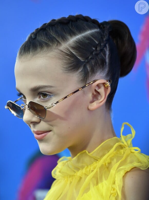 Millie Bobby Brown cruzou o tapete vermelho do Teen Choice Awards 2017 com óculos estilosos, cabelo preso em um coque e piercing na orelha