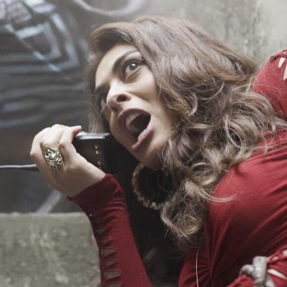 Bibi (Juliana Paes) invade a casa de uma moradora e, com arma em punho, exige que ela lhe entregue o uniforme de gari do marido, que usa como disfarce para escapar, na novela 'A Força do Querer'