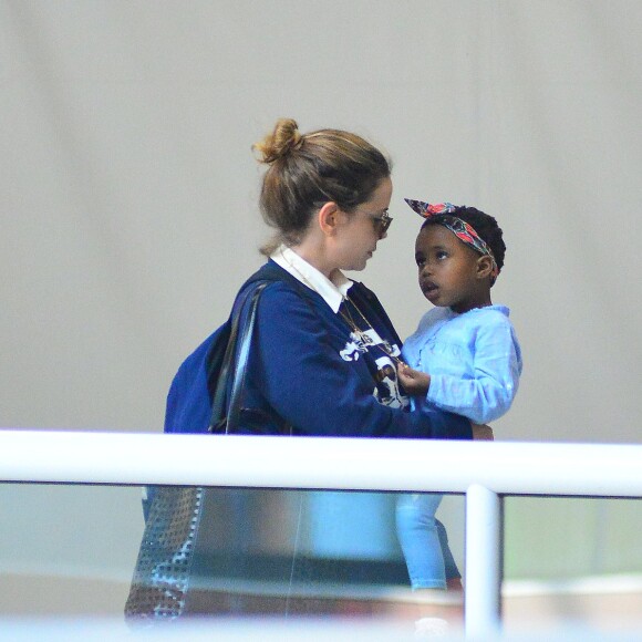 Leandra Leal caminha com a filha, Julia, no colo em aeroporto