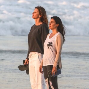 Gisele Bündchen usou camisa branca e calça branca para caminhar com amiga na orla da praia