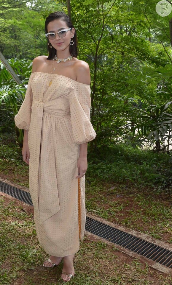 Bruna Marquezine escolheu um vestido nude ombro a ombro com amarração na cintura para prestigiar o desfile da coleção de Paula Raia em parceria com a rede de fast fashion Riachuelo