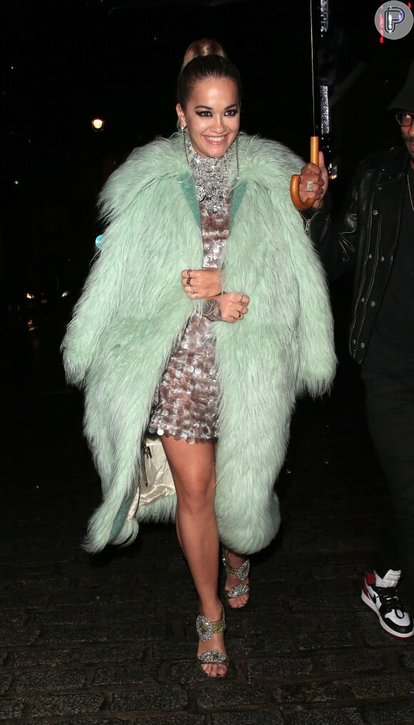 Para se proteger do frio de Londres, Rita Ora sobrepôs o vestido de paetês com um casaco de pelos verde