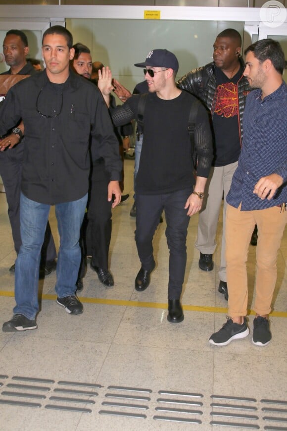 Cercado por seguranças, Nick Jonas acenou mas não parou para cumprimentar fãs em aeroporto de São Paulo