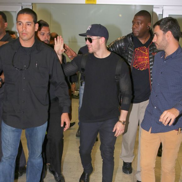 Cercado por seguranças, Nick Jonas acenou mas não parou para cumprimentar fãs em aeroporto de São Paulo