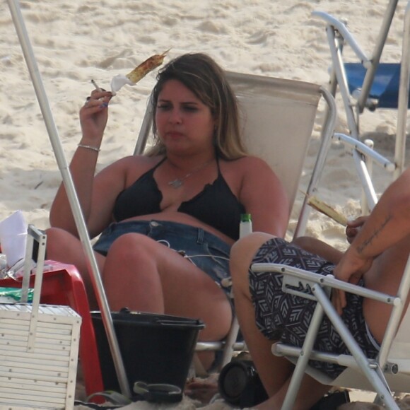 Marília Mendonça conversa com amigos na praia enquanto belisca um queijo coalho