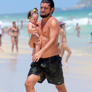 Bruno Gissoni caminha pela praia com a filha, Madalena