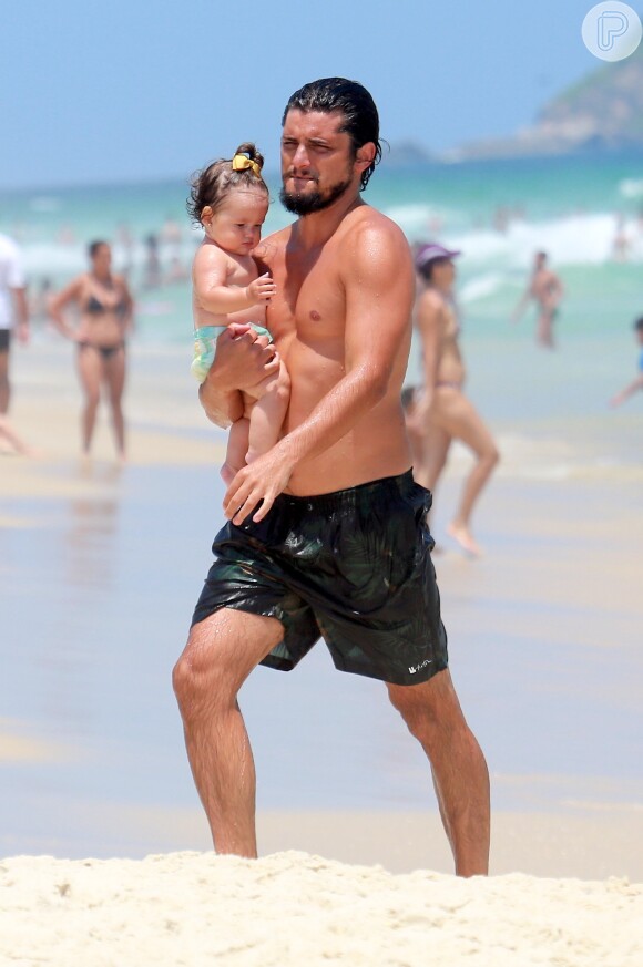 Bruno Gissoni caminha pela praia com a filha, Madalena