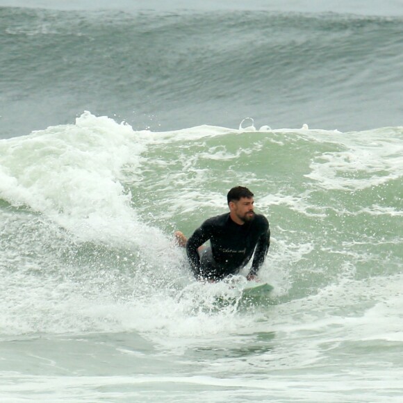 Cauã Reymond pratica surfe em dia nublado no Rio de Janeiro