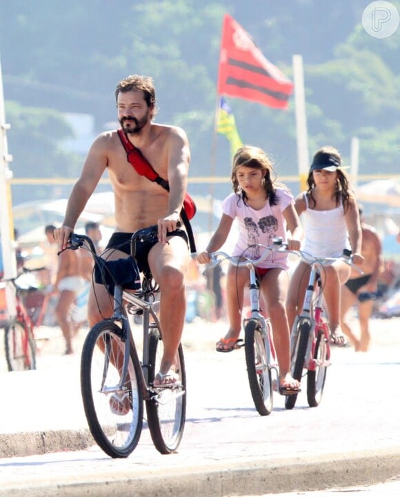 Heitor Martinez passeando de bicicleta com as gêmeas Alice e Helena, de 11 anos, frutos do antigo relacionamento do ator com Anna Markun