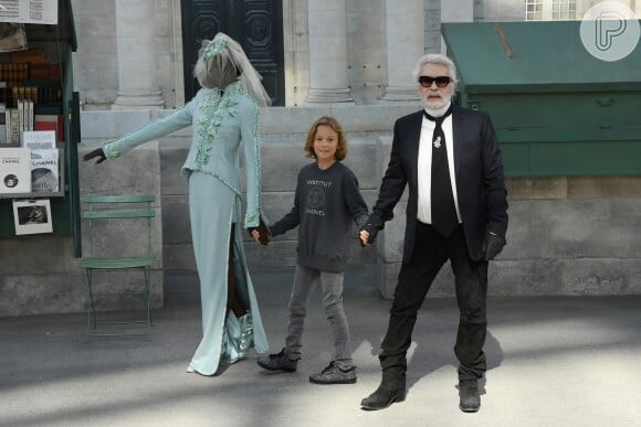 Adut Akech aguarda o momento para entrar na passarela com Karl Lagarfed, diretor criativo da Chanel, e duas crianças