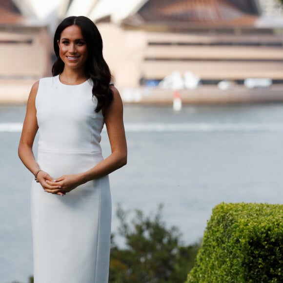 Em um dos primeiros compromissos na Austrália, Meghan deixou a barriguinha em evidência com o tubinho Karen Gee 