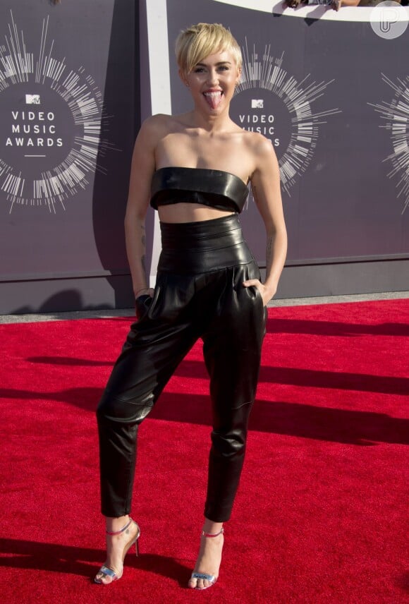 Miley Cyrus investe em um cropped top e uma calça de cintura alta preta deixando o look bem jovial