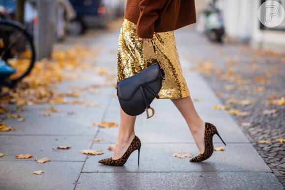 Looks metálicos: saia dourada acendendo o visual junto à Saddle Bag da Dior e scarpin em animal print