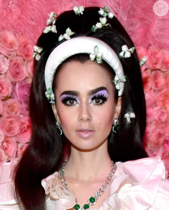 Detalhe da maquiagem e do cabelo de Lily Collins com alice band e flores adornando os fios