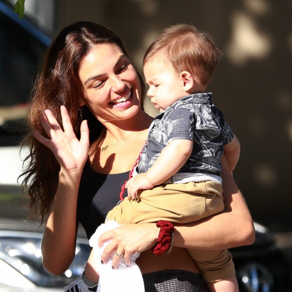 Isis Valverde, sorridente, acena para o filho, Rael, de 8 meses