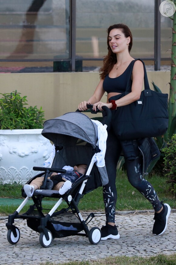 Isis Valverde deixa academia com filho, Rael, dormindo em carrinho de bebê