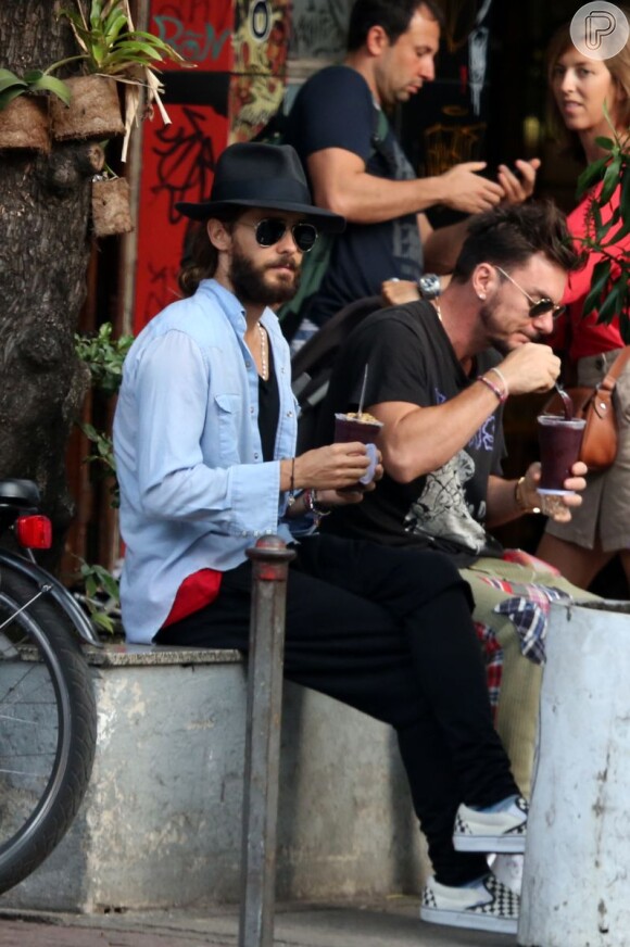 De chapéu e óculos escuros, Jared Leto toma açaí na praia de Ipanema, na Zona Sul do Rio de Janeiro, com o irmão